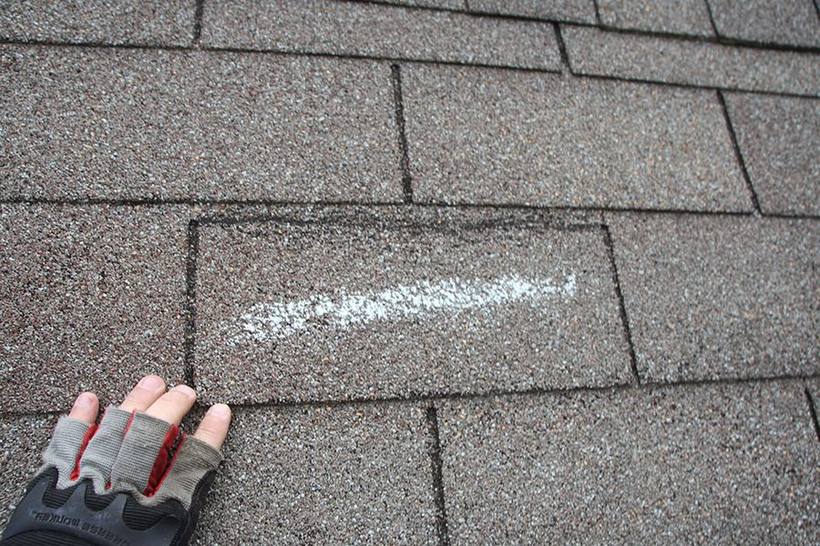 Chalk-marked hail impact documented on a shingle during inspection